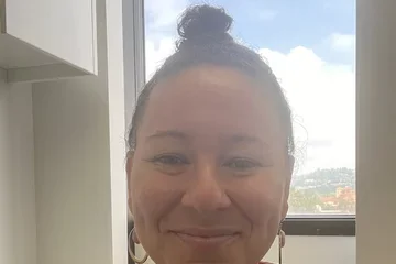 Woman in patterned shirt in front of window