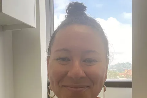 Woman in patterned shirt in front of window