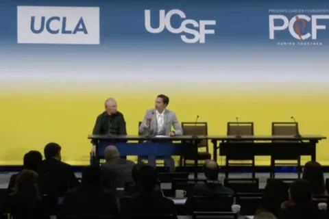 two men seated on stage in conversation