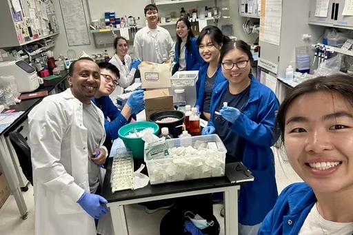 multiple people in lab coats smiling 