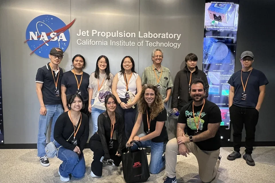 group of people standing in front of NASA sign at JPL