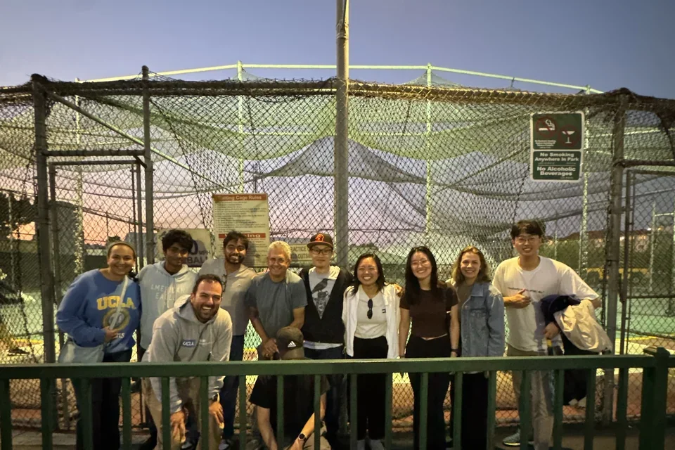 group of people standing in front of batting cages