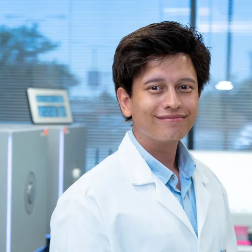 man with dark hair wearing lab coat