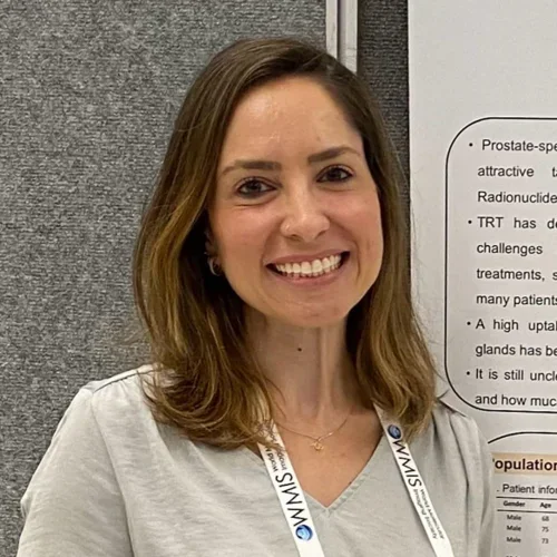 woman with dark shoulder length hair and a light top next to a poster