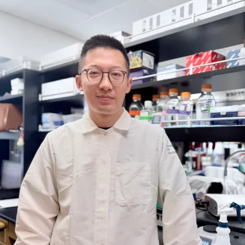 man with short dark hair wearing glasses in lab