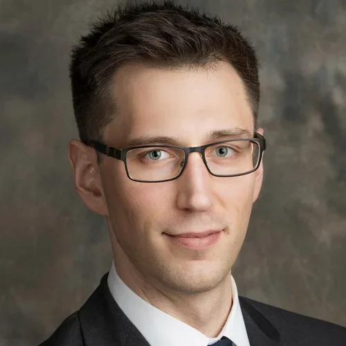 male wearing black jacket, white shirt, tie and glasses
