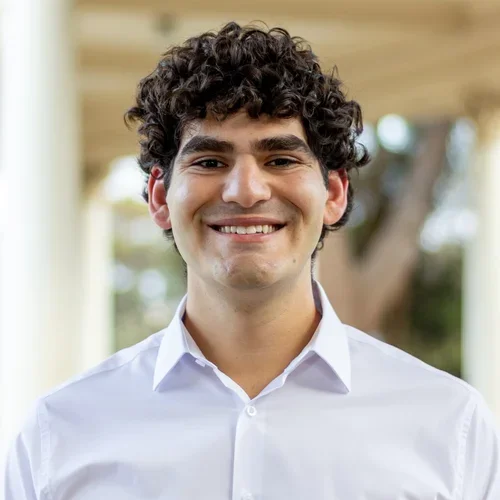 man in white shirt, curly brown hair, standing outside