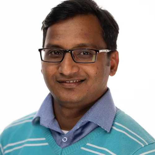 man with glasses and blue sweater with white stripes