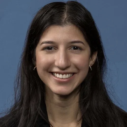female with dark hair wearing a dark blazer smiling at camera
