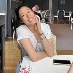 female in white shirt, sitting at a table smiling