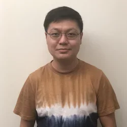 male with glass in gold shirt