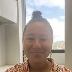 Woman in patterned shirt in front of window