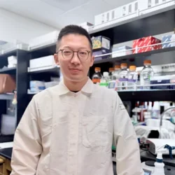man with short dark hair wearing glasses in lab