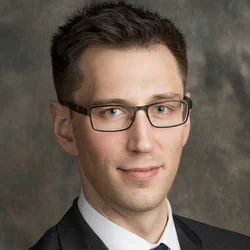 male wearing black jacket, white shirt, tie and glasses