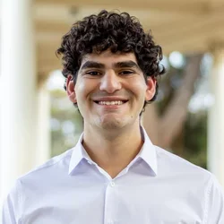 man in white shirt, curly brown hair, standing outside