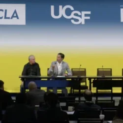 two men seated on stage in conversation