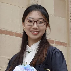 woman in black graduation robe holding flowers